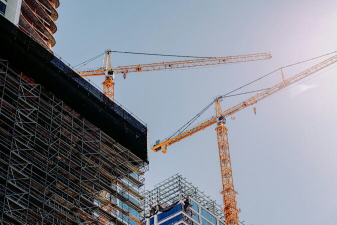Building under construction surrounded by two cranes